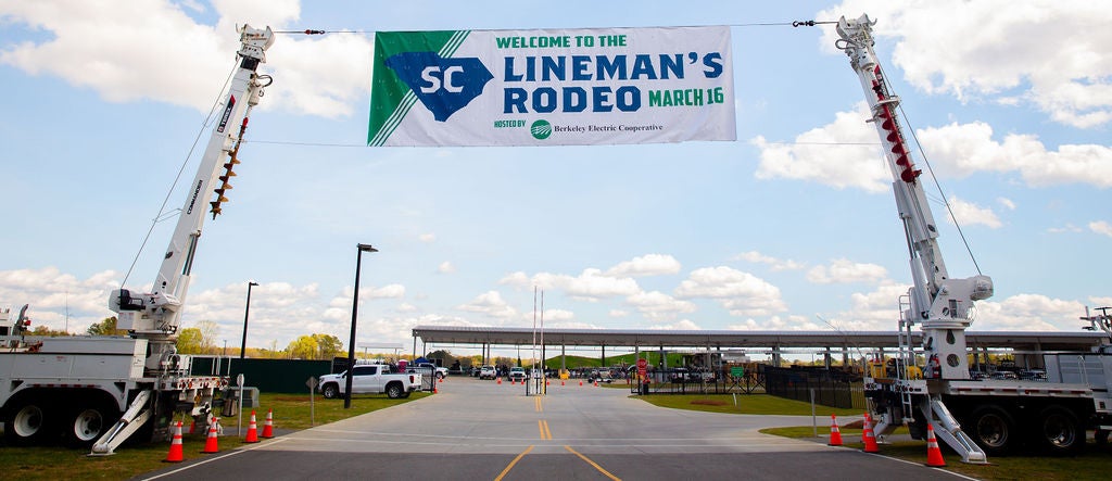 SC lineman rodeo banner hanging between two bucket trucks