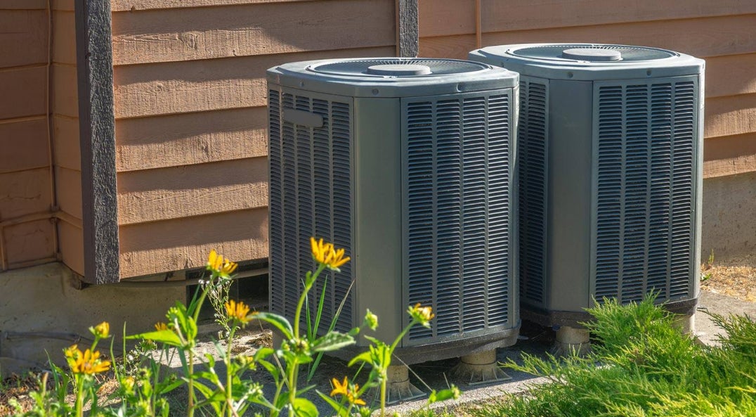 a pair of dual fuel heat pumps sitting outside a house